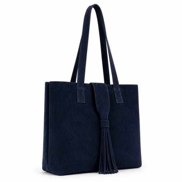 Oversized navy blue suede tote bag with straight sides, a flat base, an open top, long double shoulder handles and a long suede tassel on the front tab.