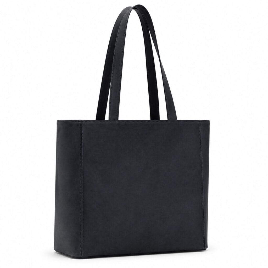 Oversized dark blue suede tote bag with straight sides, a flat base, an open top and long double shoulder handles, shown three-quarter on white.