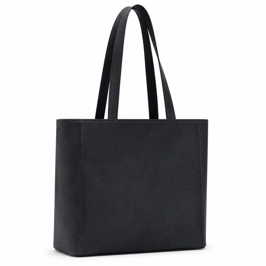 Oversized dark blue suede tote bag with straight sides, a flat base, an open top and long double shoulder handles, shown three-quarter on white.