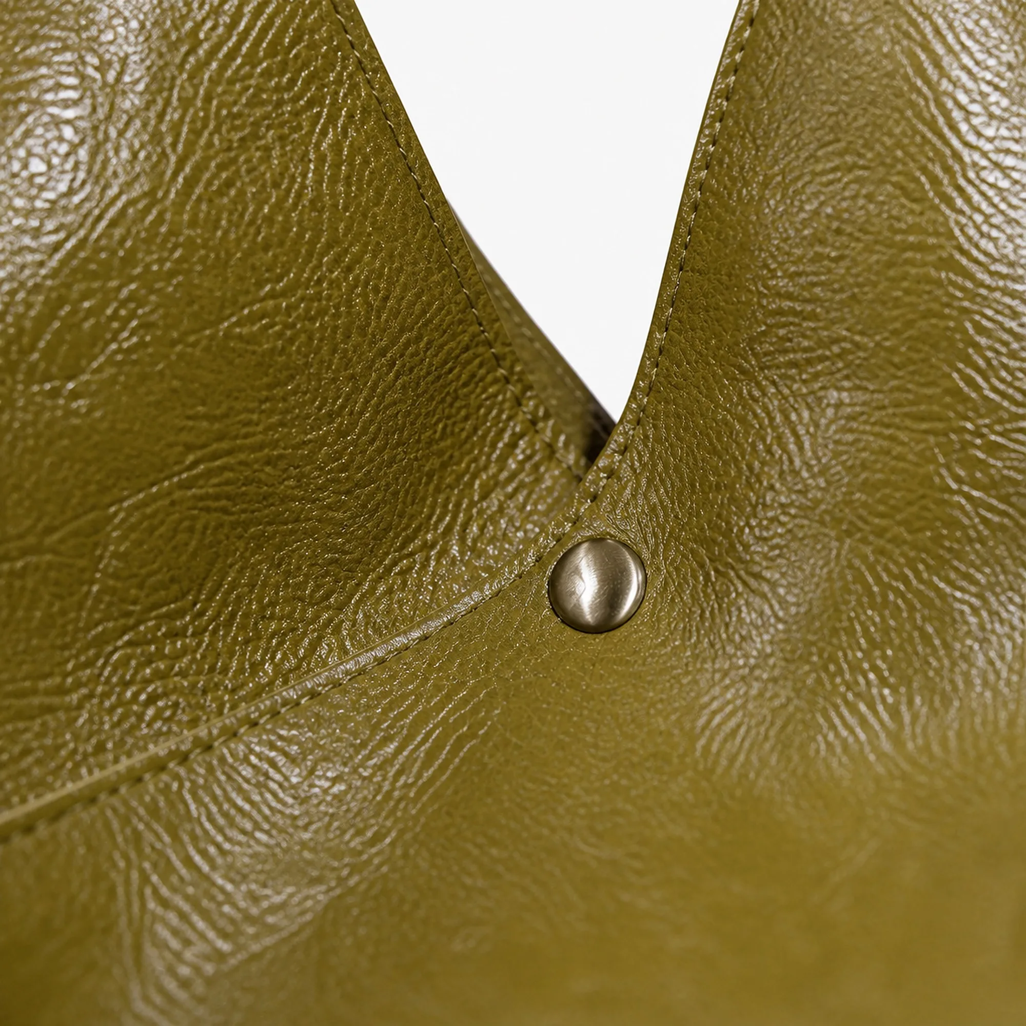 Macro of the single gold-finish magnetic snap against the semi-glossy olive leather.