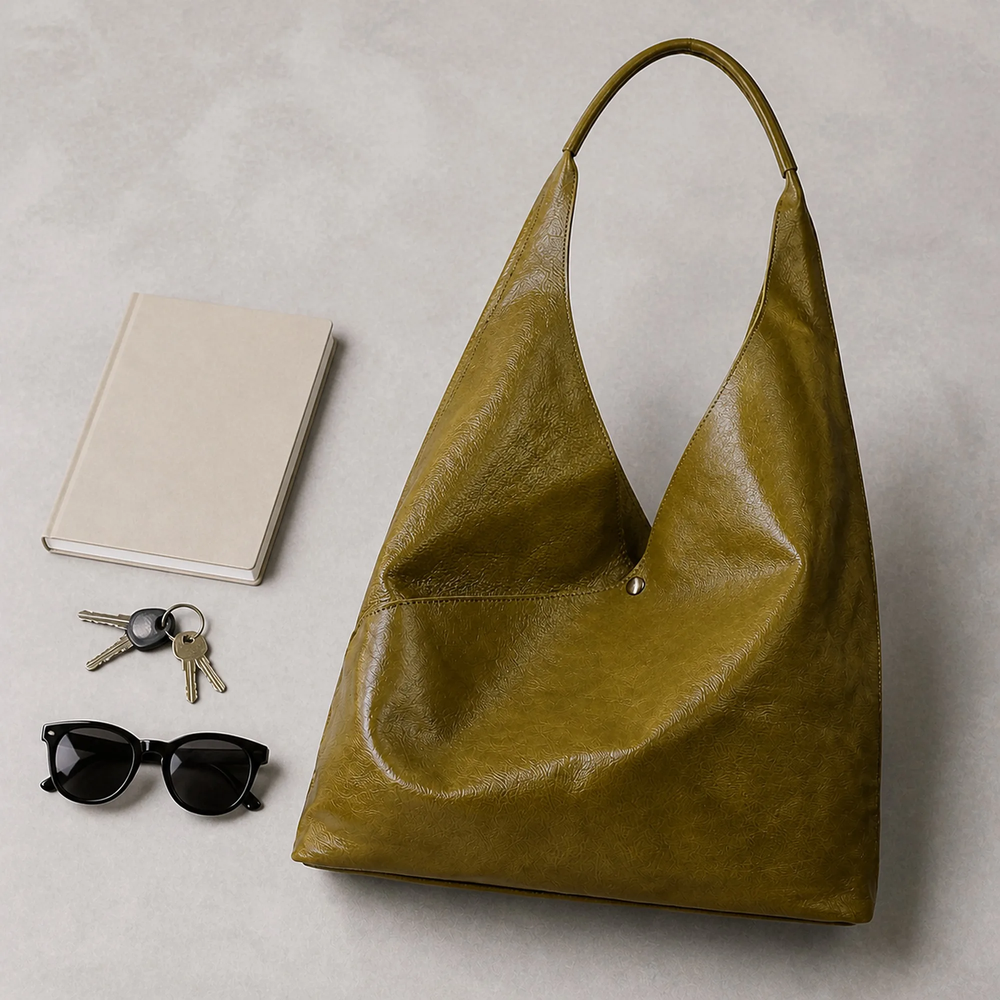 The olive green hobo beside a notebook, keys and sunglasses so its size is easy to judge.