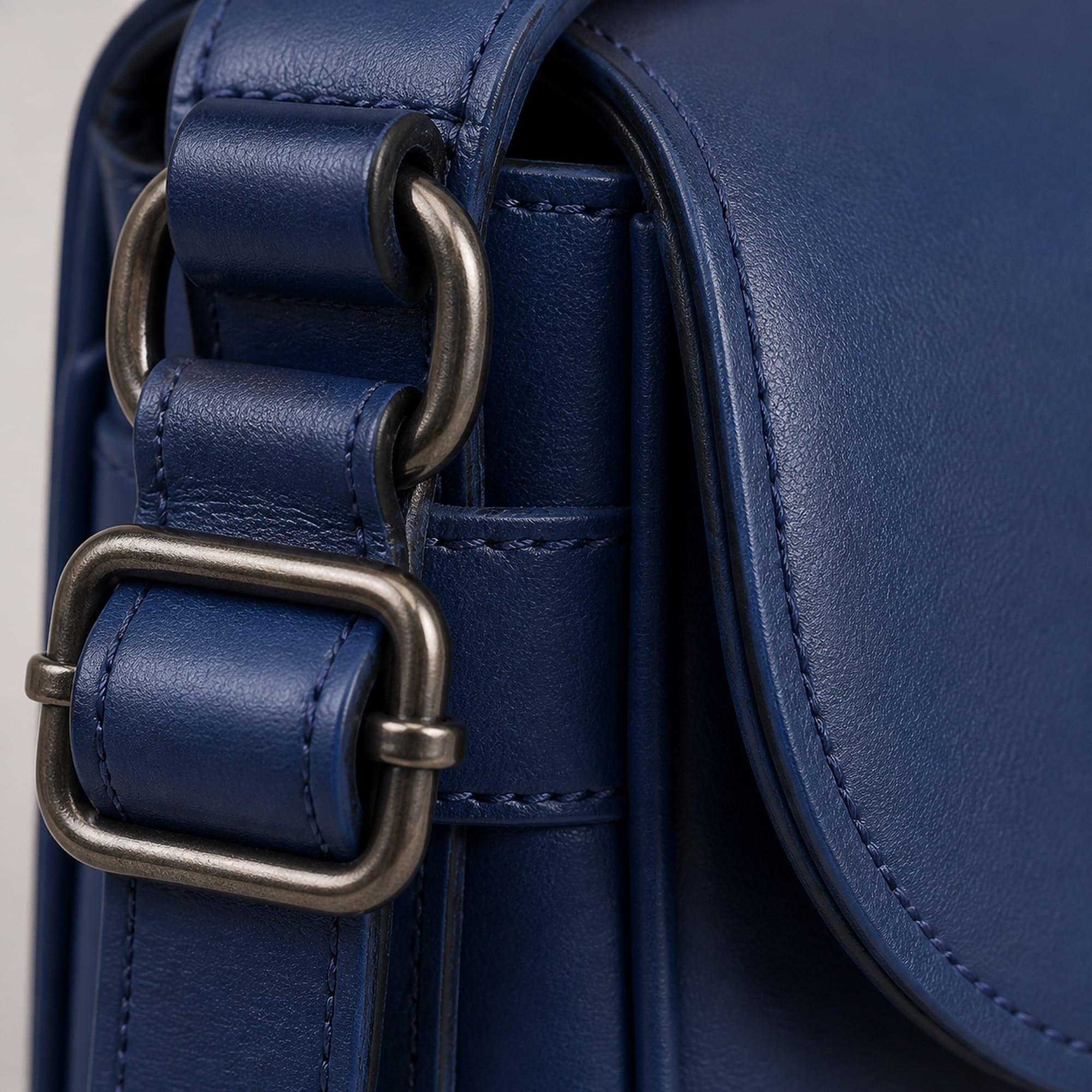 Macro of the matte dark-tone D-rings and strap adjusters against the royal blue leather.
